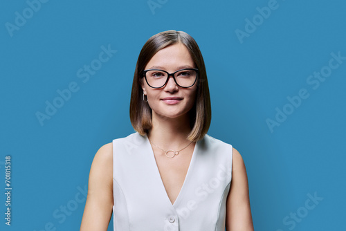 Headshot portrait of young beautiful woman in glasses, on blue studio background © Valerii Honcharuk