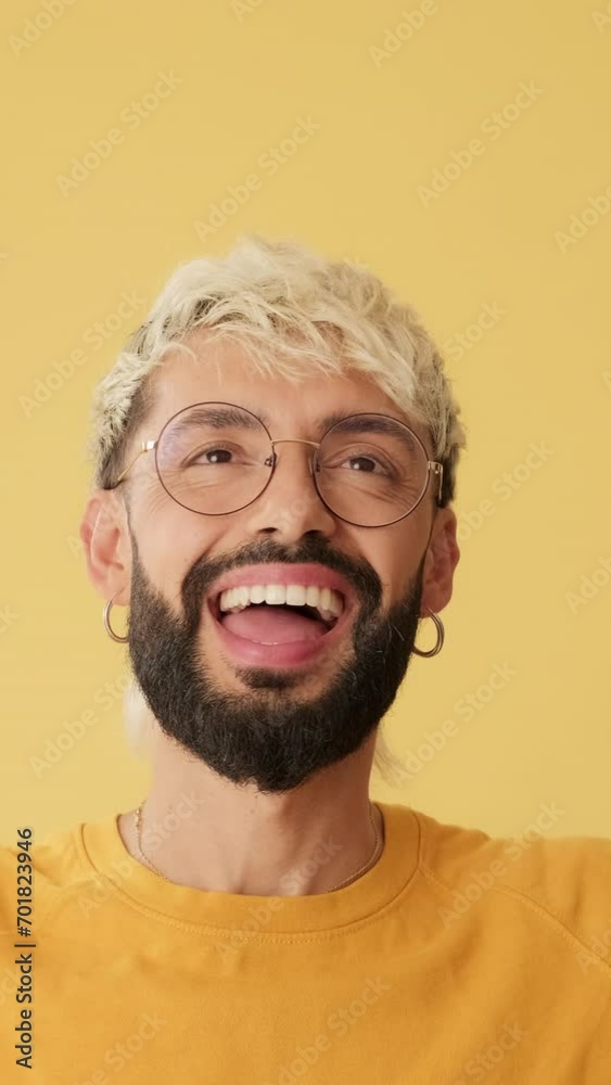 Man pointing fingers up to show mockup space isolated on yellow background in studio Man pointing fingers up to show mockup space isolated on yellow background in studio