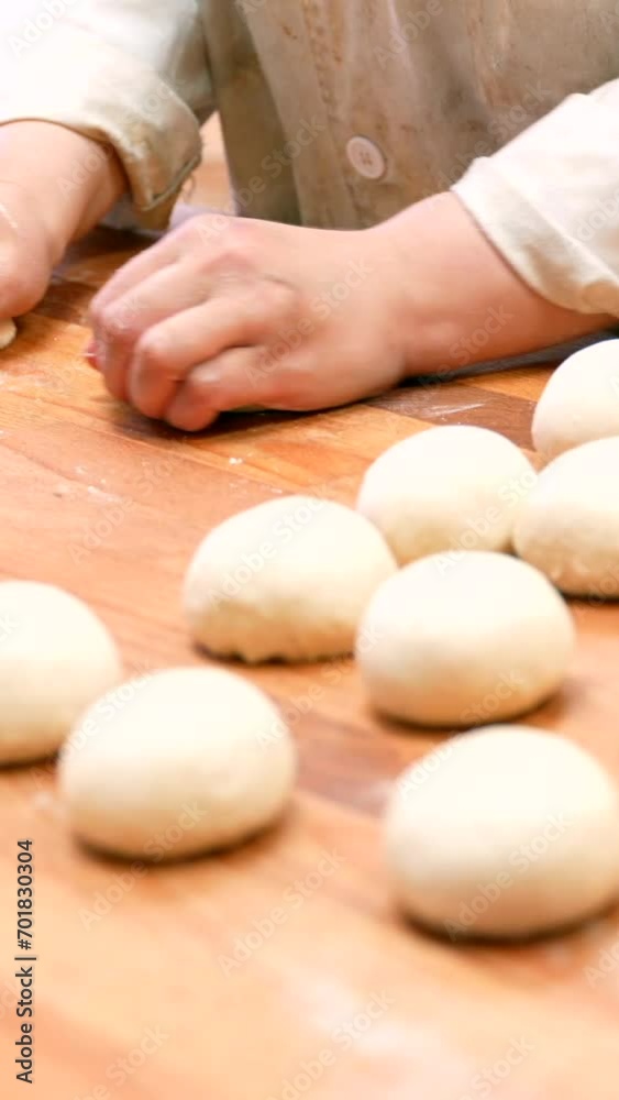 Woman breadmaker employee in the artisan bakery workshop preparing the dough in a circle Woman breadmaker employee in the artisan bakery workshop preparing the dough in a circle