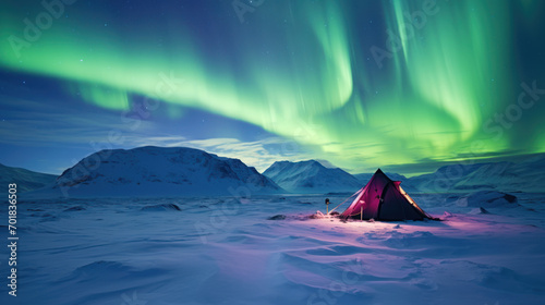 Illuminated tent under northern lights in snowy landscape