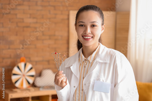 Female Asian speech therapist with logopedic probes in office photo