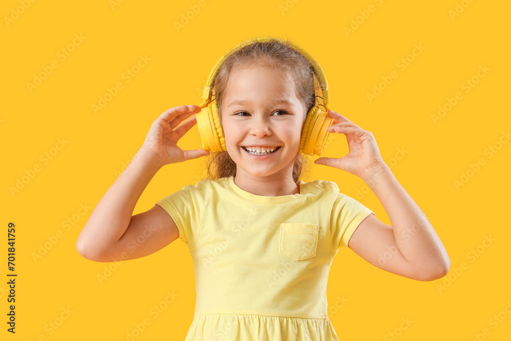 Cute little girl in headphones on yellow background Cute little girl in headphones on yellow background