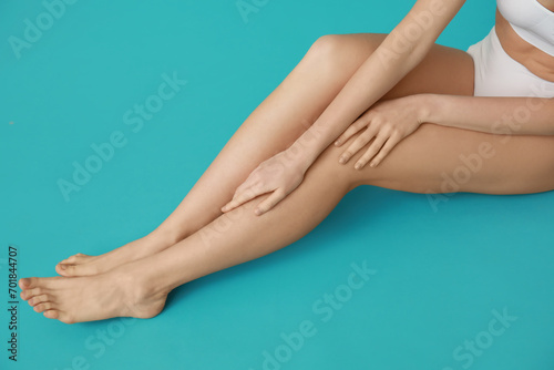 Beautiful young woman after depilation sitting on turquoise background, closeup