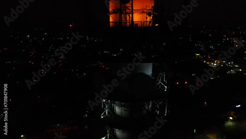 Aerial shot drone orbits to left in close up of observation tower at night photo