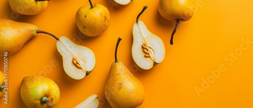 Ultrawide healthy backdrop of ripe pears on an orange background, some sliced to show the inside. photo