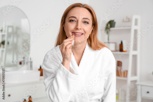 Mature woman applying lipst...