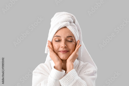 Mature woman in bathrobe after shower on light background, closeup photo
