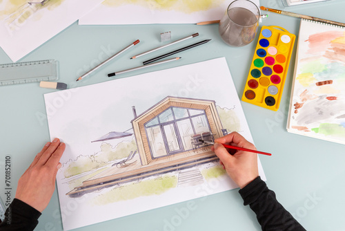 Architect illustrator working on hand drawn illustration of a modular prefabricated house  using watercolor paints and brush. photo