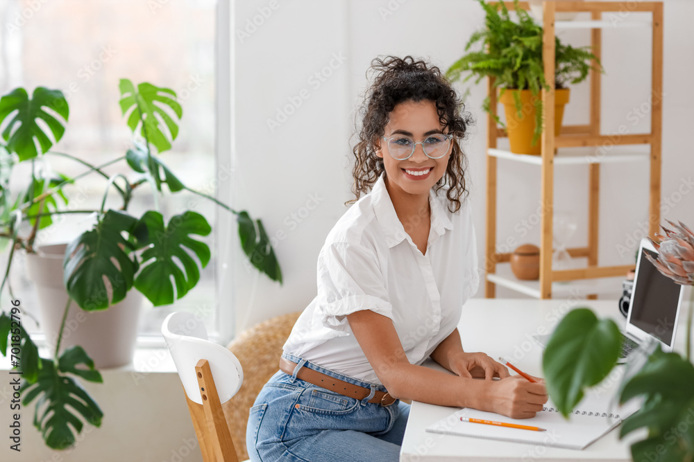 Young African-American woman writing in notebook at home office