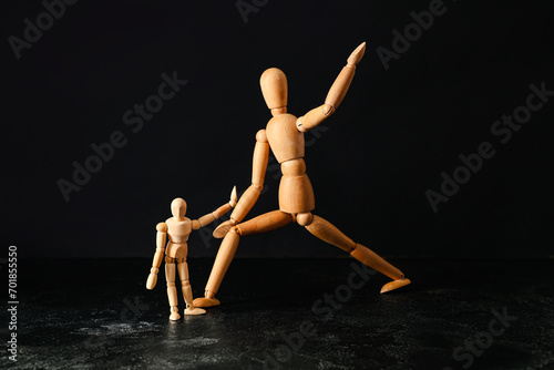 Wooden mannequins on dark background. Domestic violence concept photo