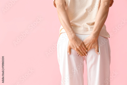 Young woman with hemorrhoids on pink background, back view photo