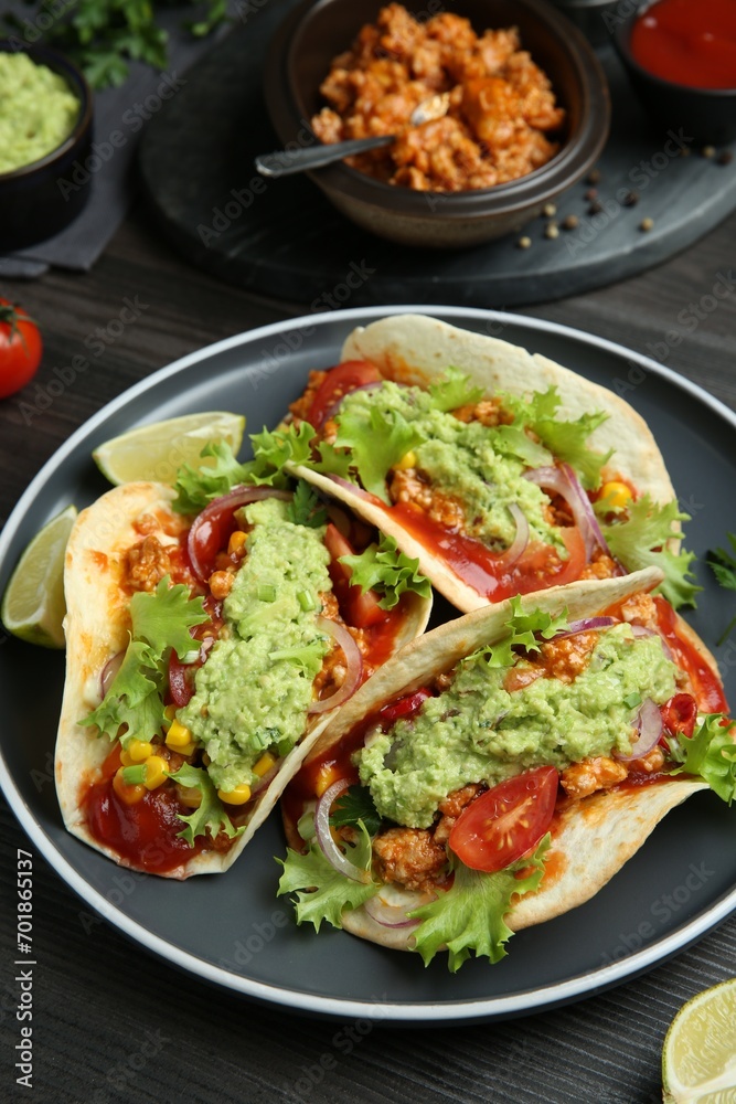 Delicious tacos with guacamole, meat and vegetables on wooden table Delicious tacos with guacamole, meat and vegetables on wooden table