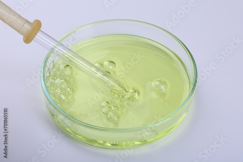 Petri dish with liquid sample and pipette on white background