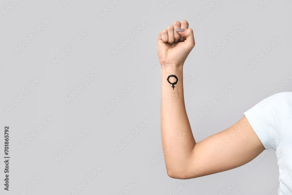 Female hand with symbol of woman on grey background, closeup. Feminism concept Female hand with symbol of woman on grey background, closeup. Feminism concept