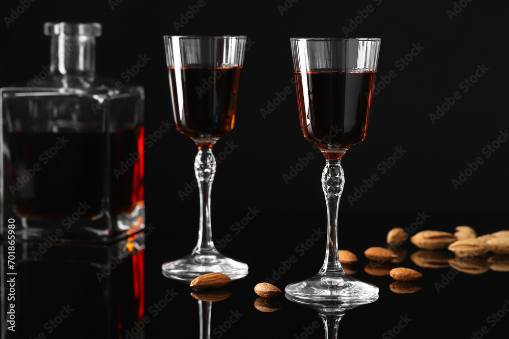 Liqueur glasses with tasty amaretto, bottle and almonds on black table, closeup Liqueur glasses with tasty amaretto, bottle and almonds on black table, closeup