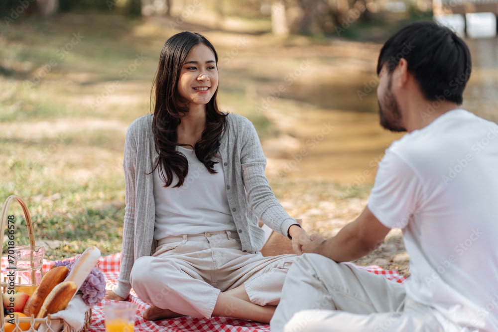 Happy romantic couple in Valentine Day asian couple hold hands for close moment together. happy couple relaxing together with picnic Basket.