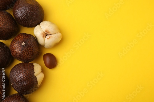 Fresh salak fruits on yellow background, flat lay. Space for text photo