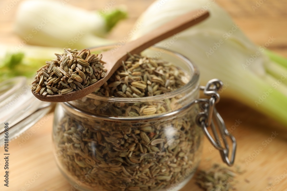 Jar and spoon with fennel seeds on table, closeup Jar and spoon with fennel seeds on table, closeup