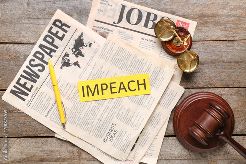Newspapers with word IMPEACH, judge gavel and scales of justice on wooden table photo