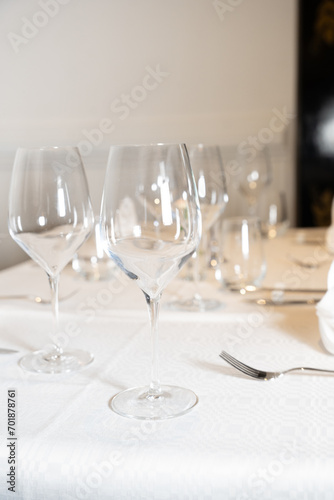 Elegant Dining Setup with Pristine Wine Glasses - A well-appointed dining table featuring sparkling wine glasses, fine silverware, and a textured white tablecloth. Perfect for restaurant advertising, 