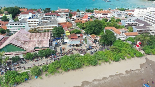 A stunning scene where a group of tourists celebrate the beauty of nature while enjoying hajat laut, an interesting cultural procession at Pangandaran Beach, West Java, Indonesia.  photo