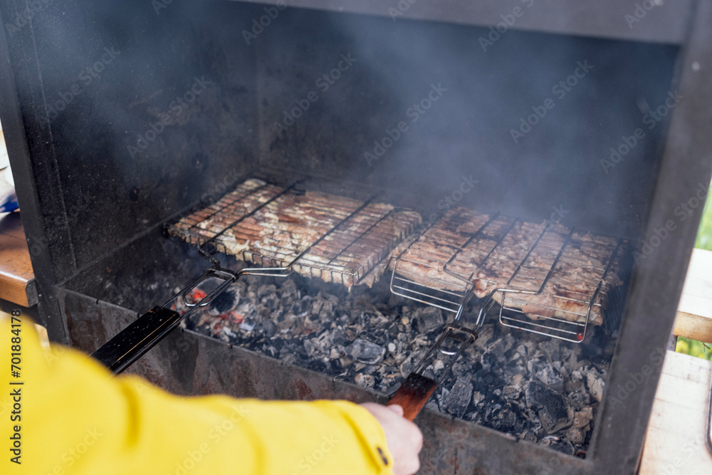 Close-up of a male hands cooking meat on grilles. Cooking juicy tasty roasted pieces of meat on coals. Delicious fresh steak on the fire on a metal grids on the outdoors. Close-up of a male hands cooking meat on grilles. Cooking juicy tasty roasted pieces of meat on coals. Delicious fresh steak on the fire on a metal grids on the outdoors.