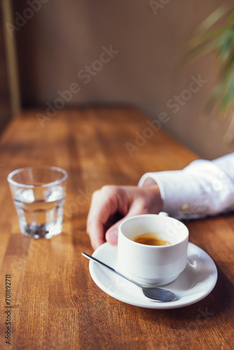 Male hand holds white cup of espresso coffee. Closeup photo with selective focus