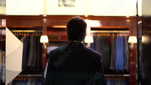 Following and back-view from the back of a man in a blue jacket that enters a department selling luxury men's clothing with wooden showcases. Style in men's wardrobe. Wealth and high level of service