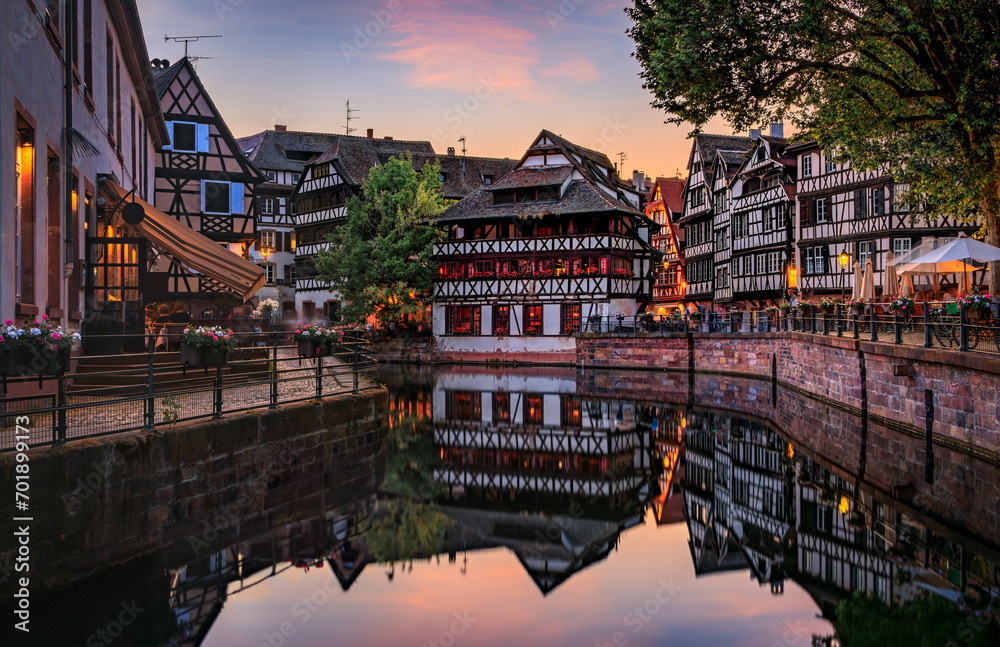 Ornate traditional half timbered houses with blooming flowers along the canals in the Petite France district of Strasbourg, Alsace, France at sunset