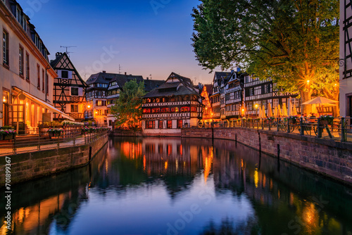 Ornate traditional half timbered houses with blooming flowers along the canals in the Petite France district of Strasbourg, Alsace, France at sunset photo