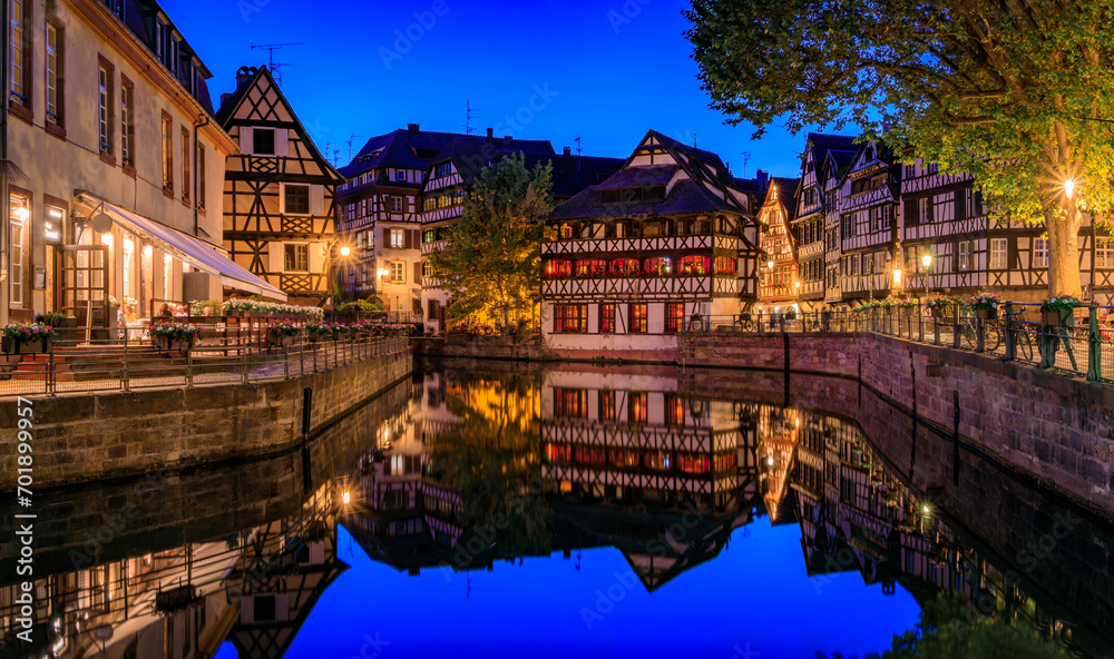 Ornate traditional half timbered houses with blooming flowers along the canals in the Petite France district of Strasbourg, Alsace, France at sunset