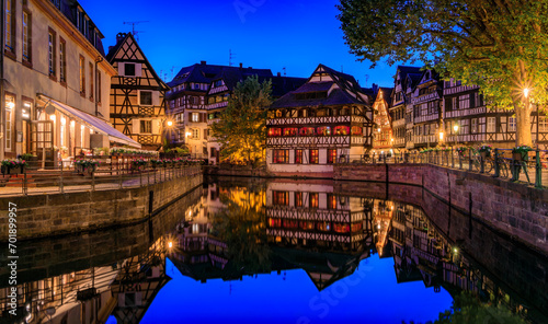 Fototapeta Naklejka Na Ścianę i Meble -  Ornate traditional half timbered houses with blooming flowers along the canals in the Petite France district of Strasbourg, Alsace, France at sunset