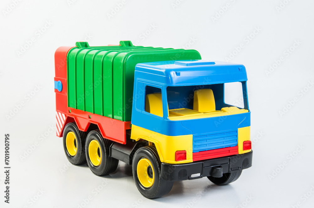Multi-colored plastic toy trucks for children's games on a white background. Garbage truck.