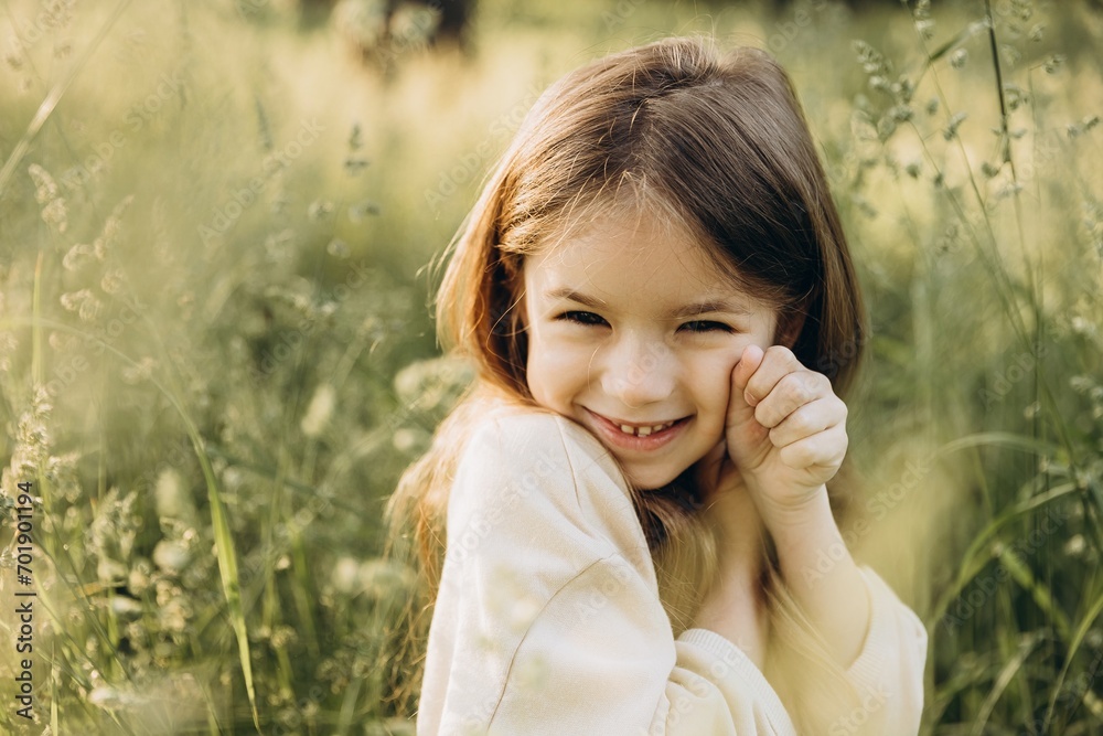 portrait of a cute smiling girl with beautiful hair posing for a photo in the middle of tall grass in a coniferous forest at sunset portrait of a cute smiling girl with beautiful hair posing for a photo in the middle of tall grass in a coniferous forest at sunset