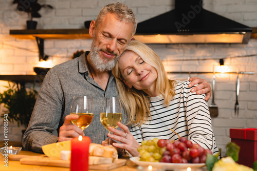 Relaxed loving middle-aged couple celebrating special event during romantic date in the kitchen