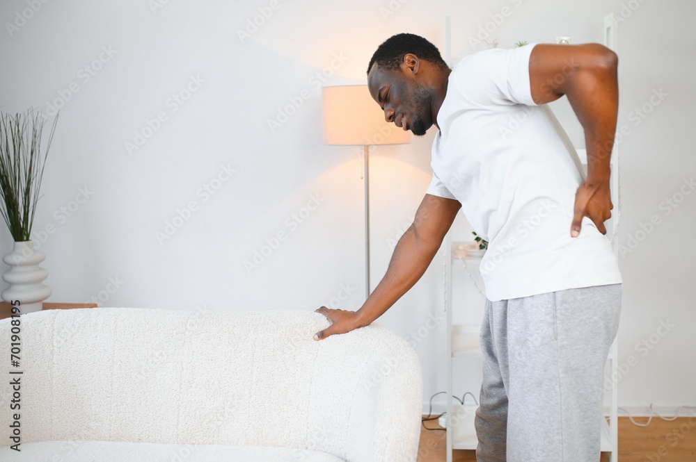 African American guy suffering from back pain, leaning on sofa, cannot walk at home African American guy suffering from back pain, leaning on sofa, cannot walk at home
