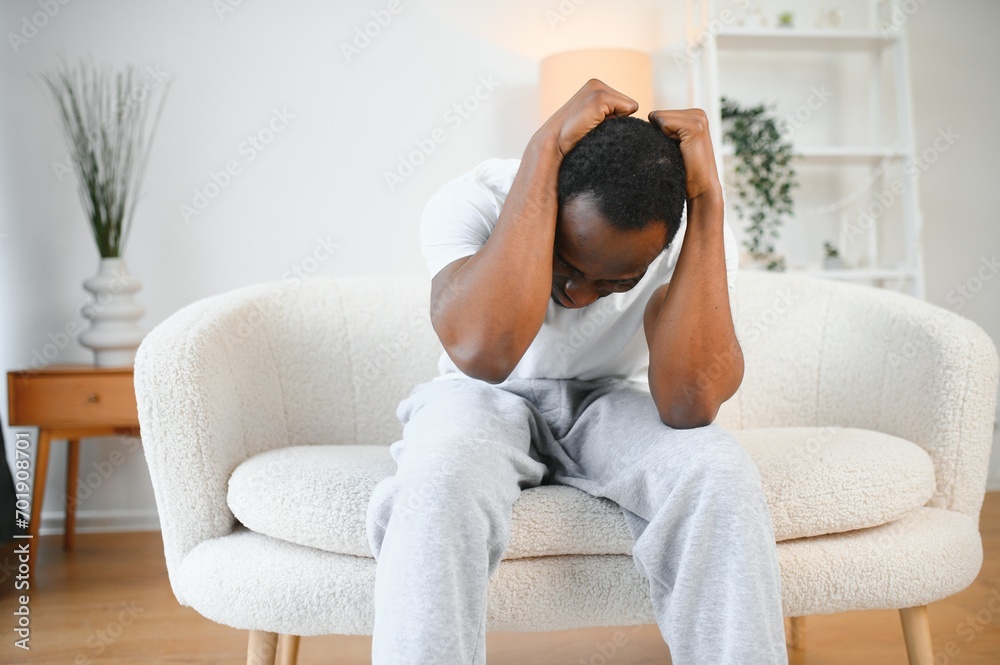Upset african-american man squeezing head with hands, writhing in pain, suffering from headache at home, copy space Upset african-american man squeezing head with hands, writhing in pain, suffering from headache at home, copy space