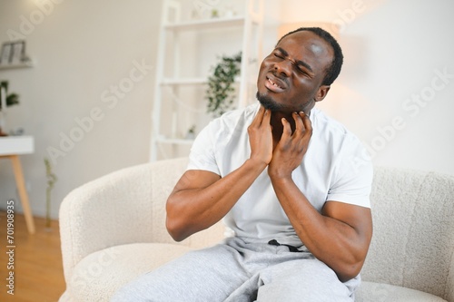 Sick African man with sore throat, Portrait of ill black man suffering from sore throat due to cold, flu, allergy photo