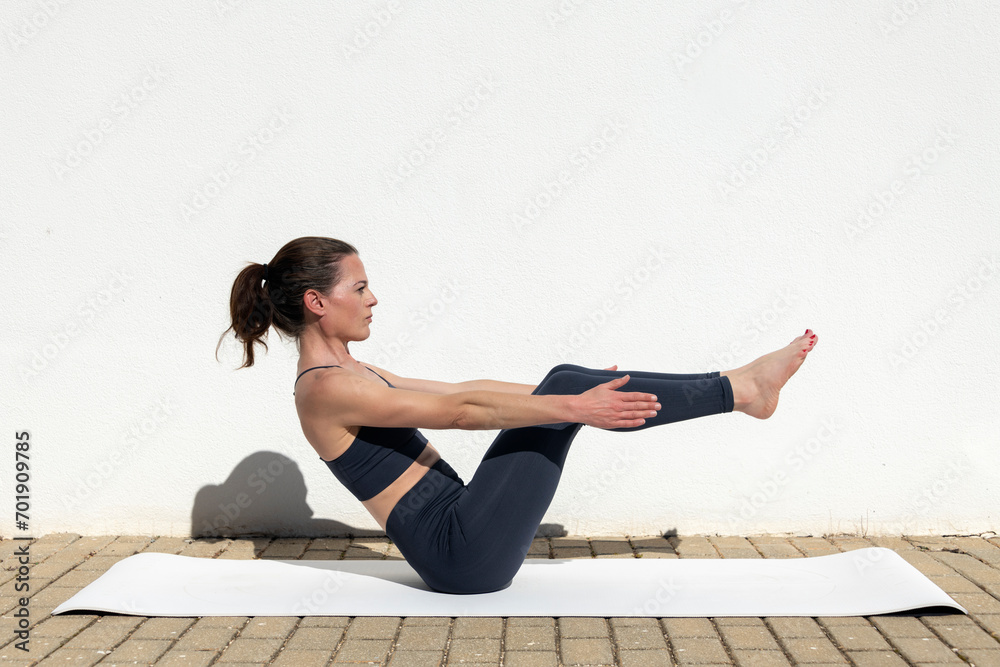 Fototapeta premium Sporty woman doing a yoga boat pose core exercise