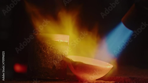 Closeup of goldsmith melting gold in crucible with blow torch photo