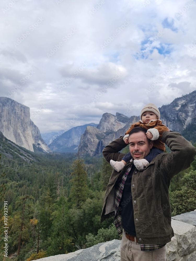 Father and son vacation on the beautiful mountain view at Tunnel view of Yosemite National Park, Father Ecuadorian and sun mix Asian on vacation, Son sitting on daddy's shoulder with the mountain view