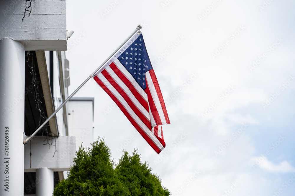 American flag hanging from a flag pole on a facade.