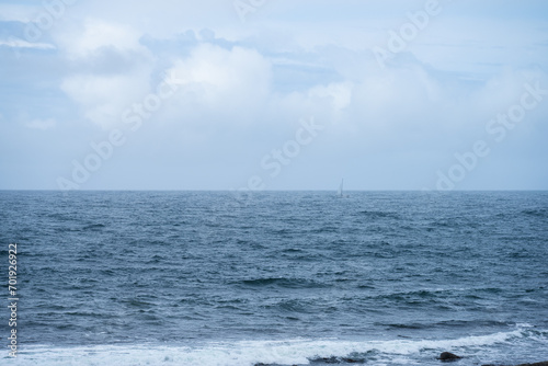 Sailboat barely visible in bad weather at sea.