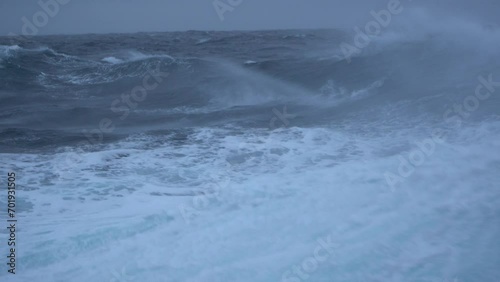 Storm. High waves. White foam on wind. Side view low on water. Wind breaks waves. Splashes