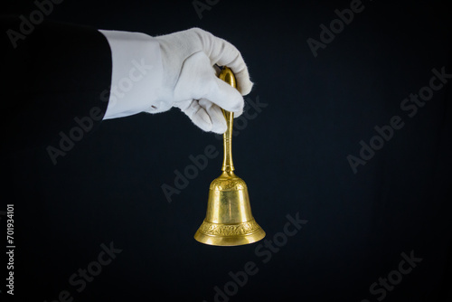 Isolated Image of White Gloved Hand Holding Gold Bell. Ring for Service Concept. Professional Hospitality and Elegance.