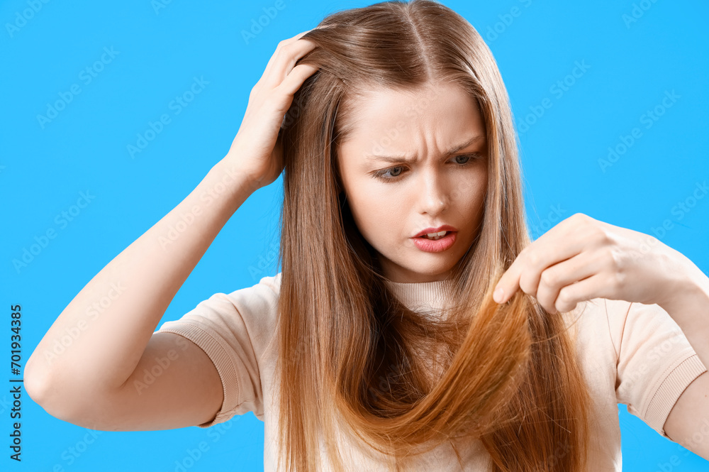 Worried young woman with hair loss problem on blue background Worried young woman with hair loss problem on blue background