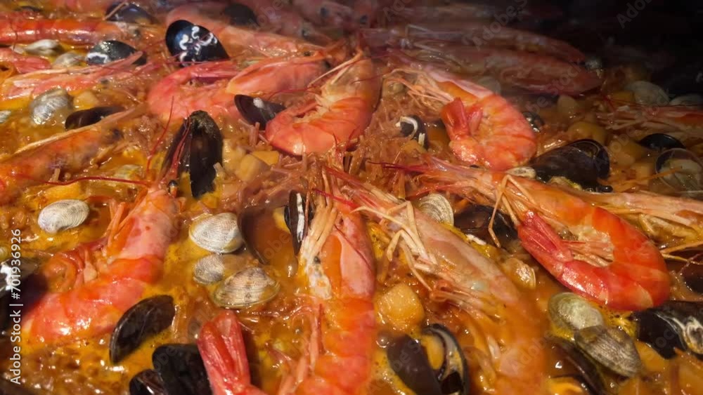 Fideuá cooking in a large pan with fish and seafood. Fideuá cooking in a large pan with fish and seafood.