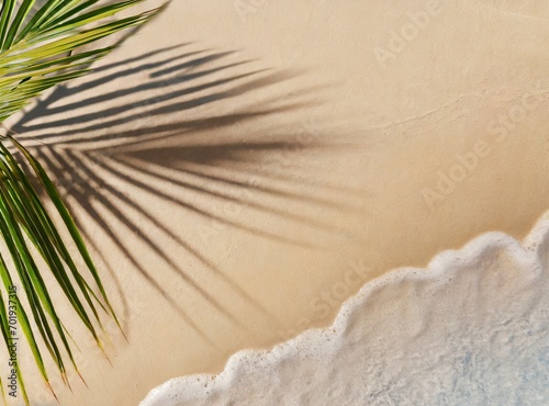 Idyllic empty sand beach with water wave and palm leaf shadow from above, beautiful sunny summer vacation background with copy space for text or product presentation, flat lay