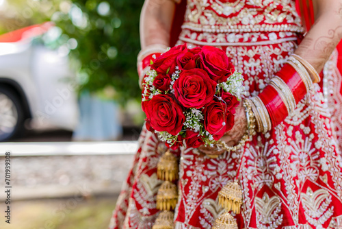 Indian bride's holding a bouquet of red roses close up