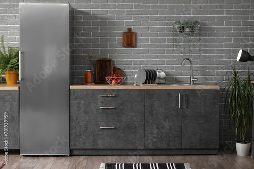 Interior of modern kitchen with grey counters, fridge and houseplants photo